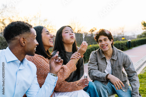Bild auf Leinwand Young diverse friends enjoying leisurely outdoor playtime, blowing soap bubbles