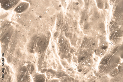 Transparent cosmetic gel, texture on a beige background, close-up.