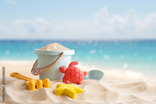 Beach toys set from plastic bucket, rake, shovel and molds on tropical sand with space