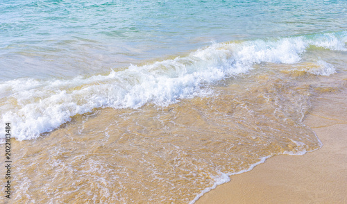 Foto Gentle ocean waves lapping against sandy beach shoreline in sunlight