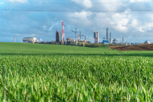 A large petrochemical enterprise on the background of a wheat field. Next to the agricultural field there's a factory for the production of chemical fertilizers. smoke escapes from factory chimneys