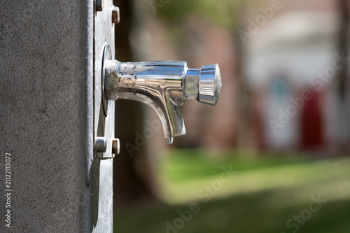 Foto Una gota de agua cuelga del grifo de una fuente pública en un parque