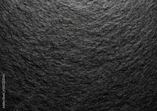 Textured close-up of dark, rough, layered surface. Grey and black tones