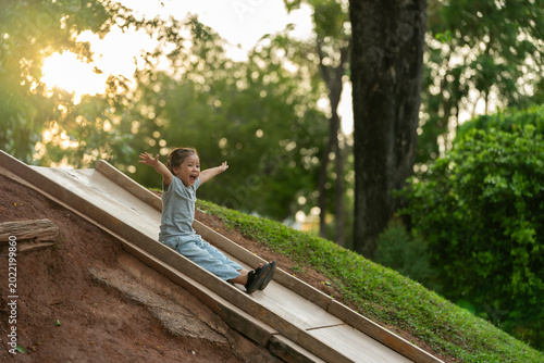 happy preschool child girl sliding and playing at playground