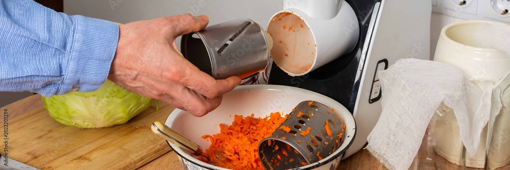 Φωτογραφία A 53-year-old man is in his kitchen preparing cabbage and carrots for fermentation