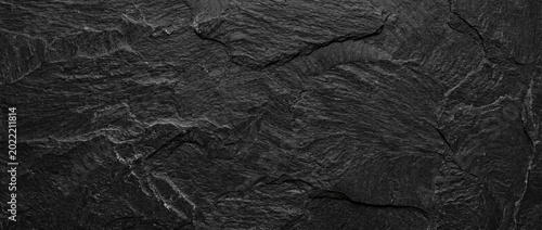 A rough-textured natural slate surface in deep gray and black tones. A natural stone texture with a rustic yet modern look, ideal as a backdrop for design projects.