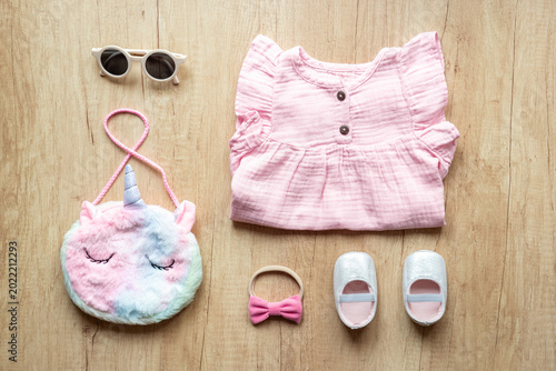 Obraz na płótnie Baby girl pink cotton muslin dress with shoes and unicorn-shaped accessories, top view