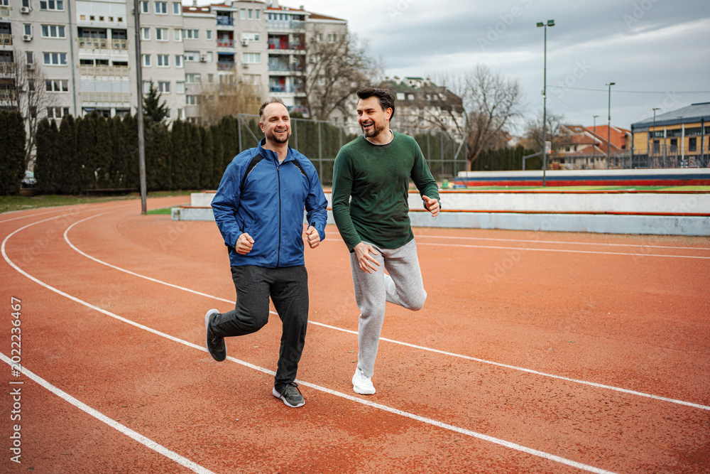 Fototapeta premium Two men friends jogging on running track