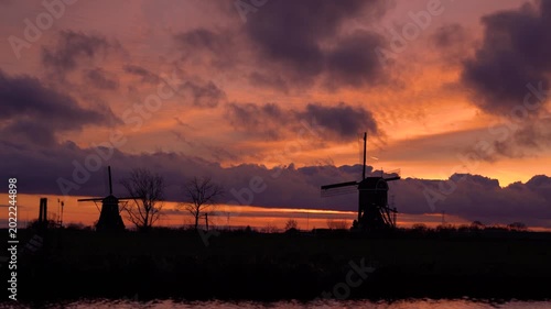 Traditional Dutch Windmill Silhouettes Against Vibrant Red Sunset Sky
