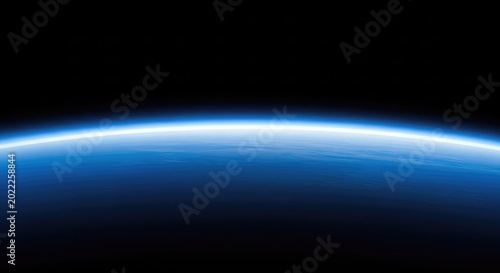 A breathtaking view of the curved planetary horizon showing a vibrant blue atmospheric glow transitioning into the deep black void of space, glow, blue, sunrise