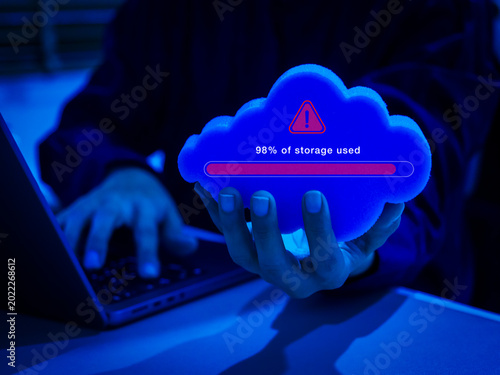 Cloud storage full concept with red warning icon, and progress bar showing data capacity problem, server overload in person hand. System storage limit, data management issues and cloud computing risk.