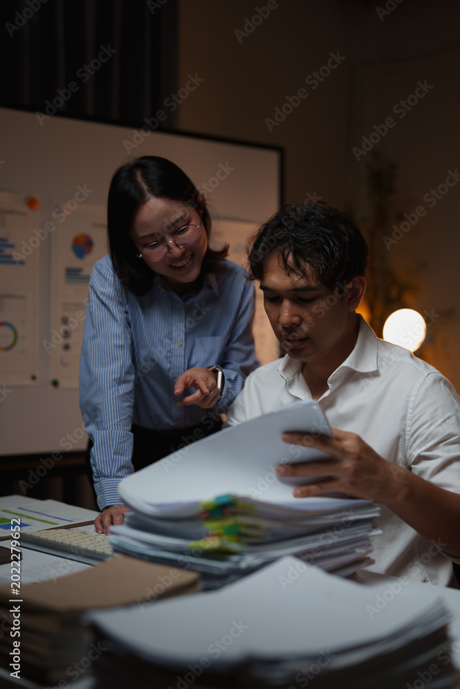 Fototapeta premium Colleagues collaborating through late night work, analyzing business documents and data, focusing on strategy and important project development in an office setting