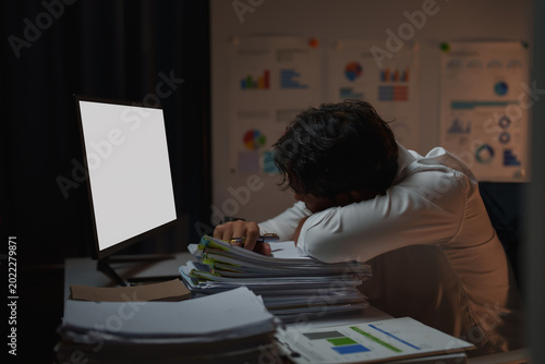 Photos Exhausted businessman sleeping at office desk after long hours, feeling overwork