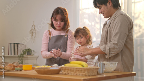 Foto The parents are helping their daughter knead dough to make bread