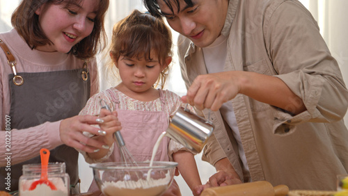 Obraz na płótnie The parents are helping their daughter knead dough to make bread