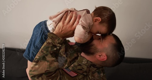 Male american soldier in military uniform having tender moment with his little son at home - Emotional military homecoming and family concept