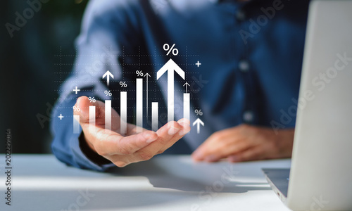 Businessman holding virtual bar chart with upward arrows and percentage symbols. Visualizing corporate performance, data-driven decision making, business scalability, and revenue optimization