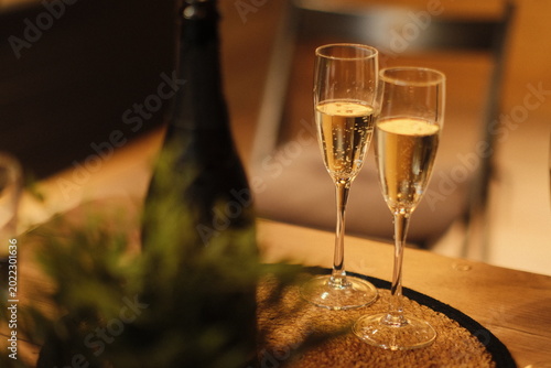 Foto Two glasses of champagne and a bottle on a table in warm golden light
