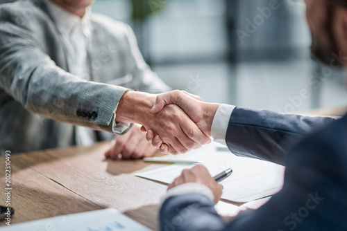 Two professionals shake hands over a wooden table