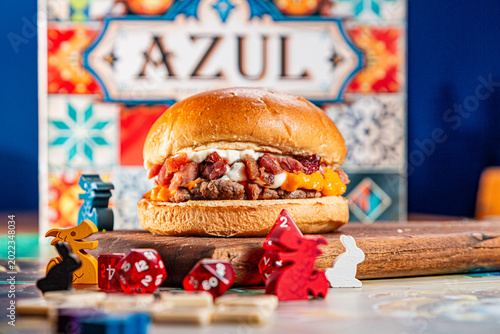 Fotografie Gourmet Beef Burger with Bacon and Caramelized Onions on Board Game Background