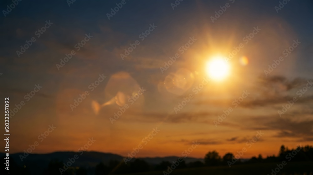 Obraz premium Sunset over peaceful rural landscape with glowing sun and vibrant sky colors