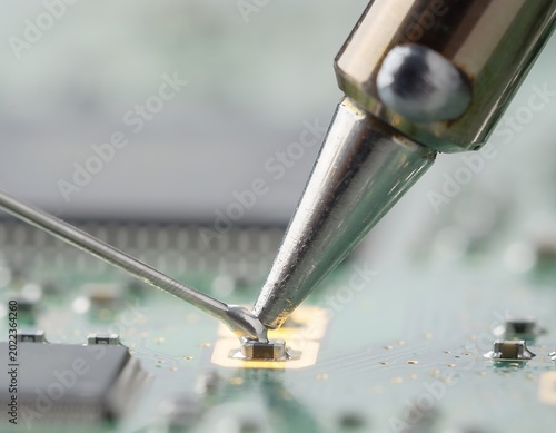 Close-up of Soldering Iron Working on a Circuit Board for Electronics Repair.
