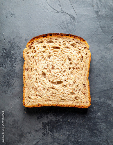 A slice of whole meal bread on grey stone background 