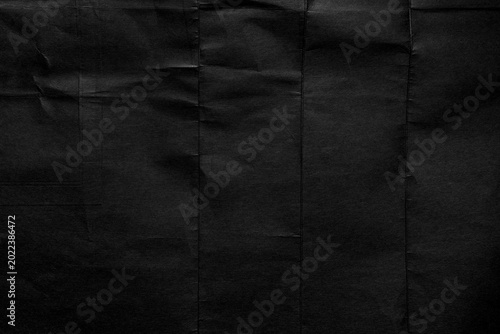 Black abstract background with old crumpled dark paper texture, creases and fine linear fiber structure. Minimalist monochrome backdrop 