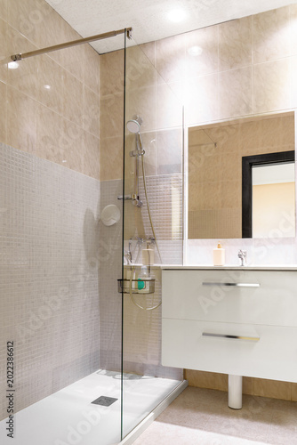 Clean interior of a modern hotel bathroom featuring a walk-in shower with a sleek glass partition