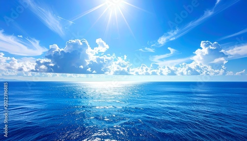 Open ocean, sparkling, under a bright sun and scattered, fluffy clouds