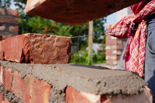 Fotografija Bricklaying Process with Red Brick and Wet Cement Mortar