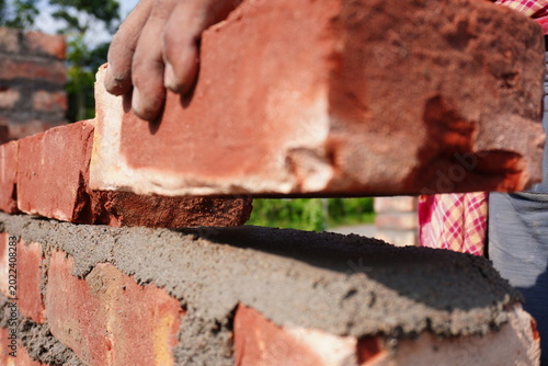 Close Up of Mason Laying Red Bricks with Cement Mortar