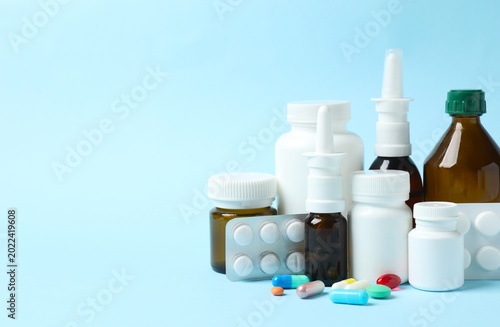 Different pills and bottles of medicines on pastel blue background, space for text