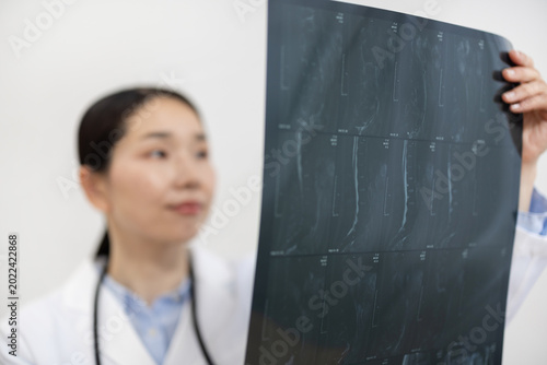 Photos Asian Female Doctor in White Coat Reviewing X-ray Image