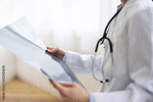 Foto Close-up of Hands of Asian Female Doctor Reviewing X-ray Image