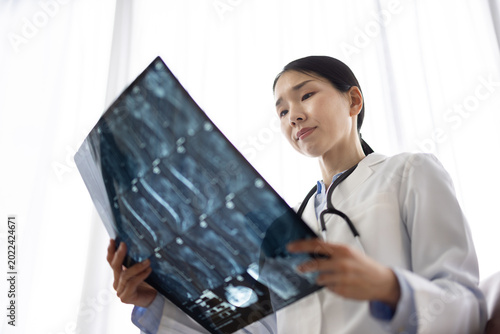 Photos Asian Female Doctor in White Coat Reviewing X-ray Image