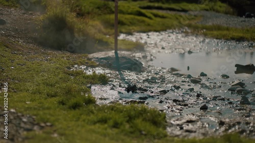 Large puddle of steaming hot spring water reflecting silhouettes of people on its surface. Tourists come to thermal springs for health improvement.
