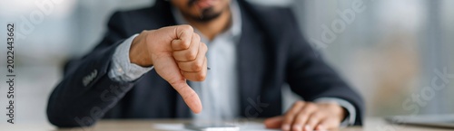 Businessman giving thumbs down gesture in office setting