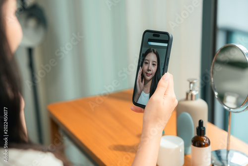 Photos Modern woman uses an AI skin analysis app at home, scanning her skin for instant