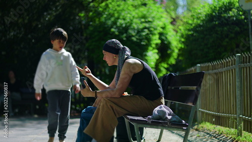 Foto Mother undergoing chemotherapy on park bench during video call, briefly guiding