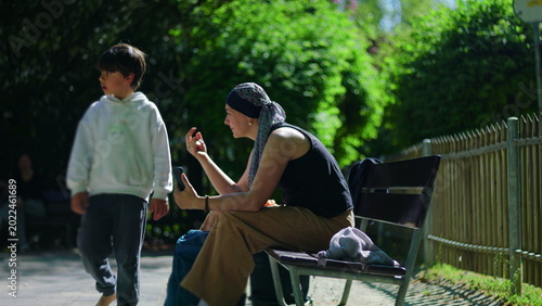 Tableau sur toile Mother undergoing chemotherapy on park bench during video call, briefly guiding