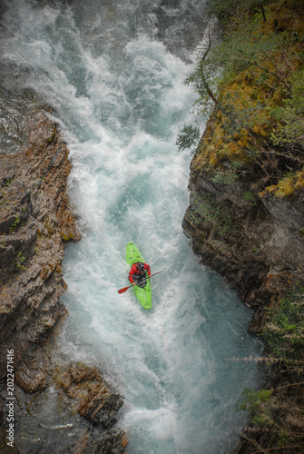 View of a kayaker in a green kayak navigating the white water rapids of the Rio Manso canyon San Carlos de Bariloche, Rio Negro, Argentina.