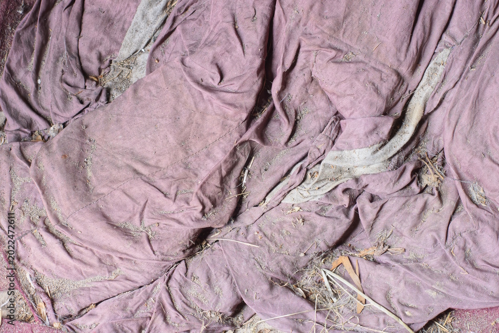 Fototapeta premium part of the old upholstery on the wall of torn brown purple fabric with holes 