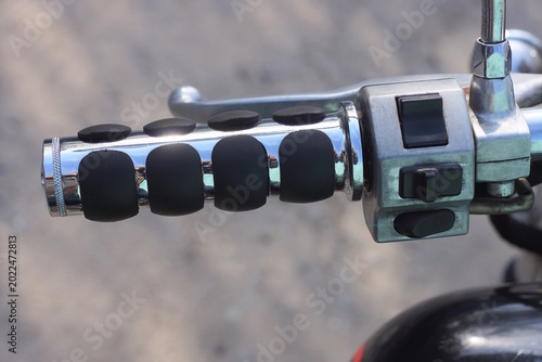 part of a old motorcycle with black gray steering wheel on the summer street