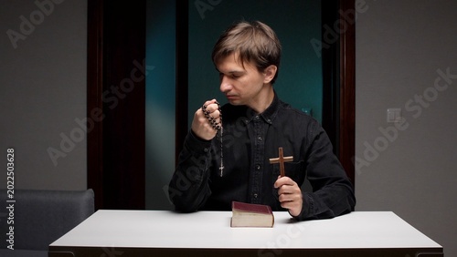Foto Man focusing on faith and spirituality, holding rosary beads and a crucifix with