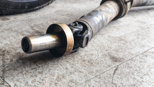 Bild auf Leinwand Close-up of a used, greasy metal automotive driveshaft with a universal joint an