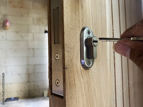 Cuadro en lienzo Hand inserting key into modern door lock cylinder on wooden door