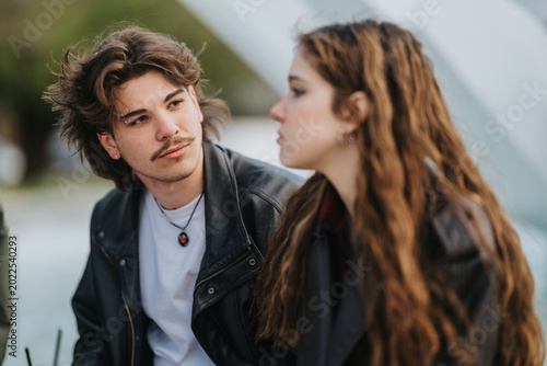 Tableau sur toile Two high school friends sit together outdoors in casual leather jackets and converse