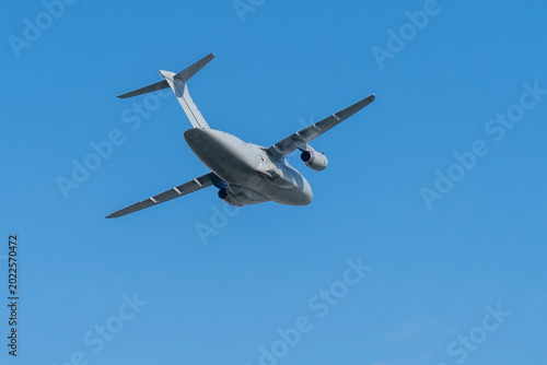 Gray hungarian military transport plane flying in the blue sky