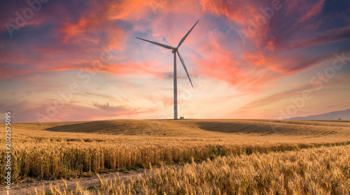 Wind Turbine Standing in Golden Wheat Field at Stunning Sunset, World Environment Day Concept of Clean Renewable Energy and Sustainable Green Power